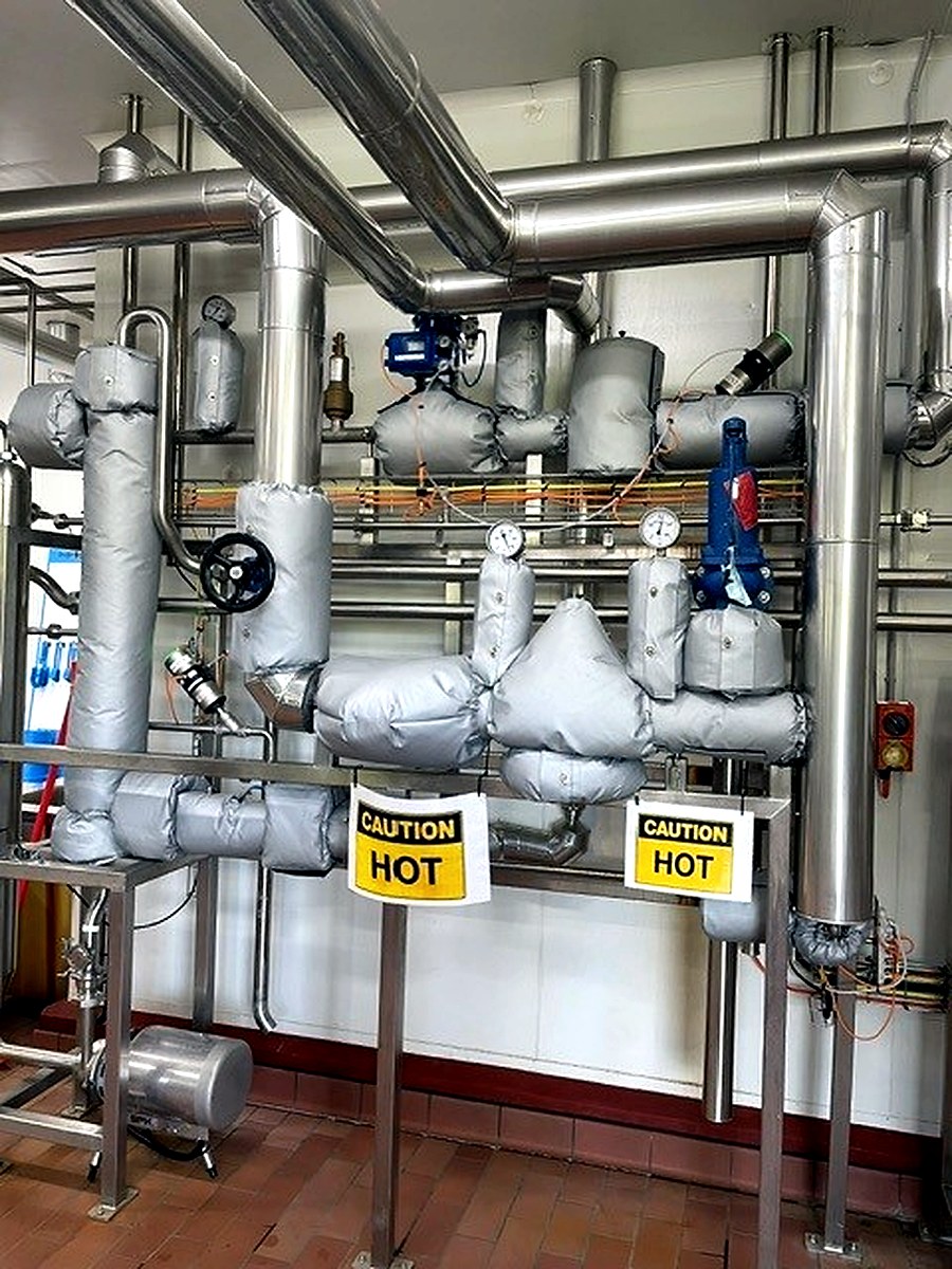 Thermal jackets on hot process pipework with CAUTION HOT warning signs visible